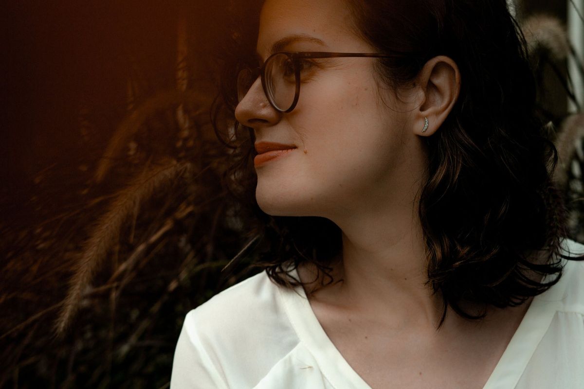Renata de perfil, sorrindo, com capim ao fundo