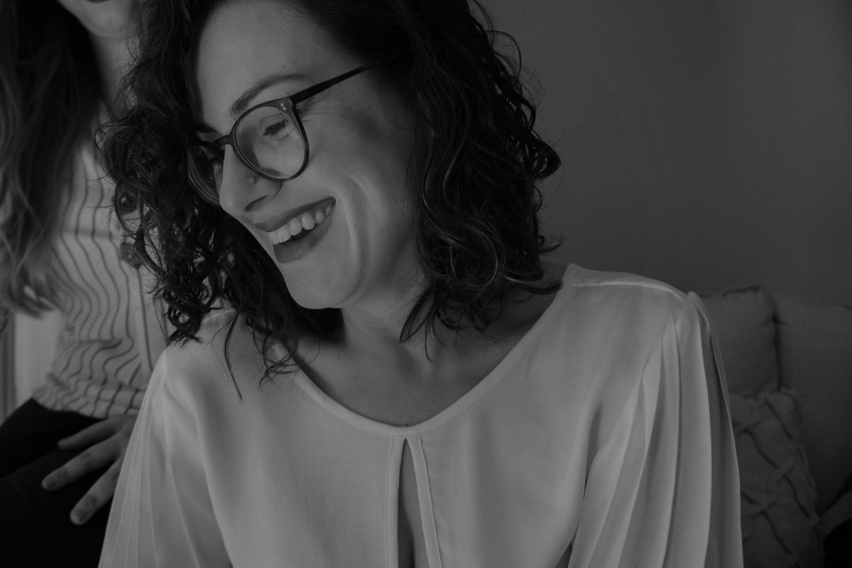 Renata rindo, olhando para baixo, em preto e branco